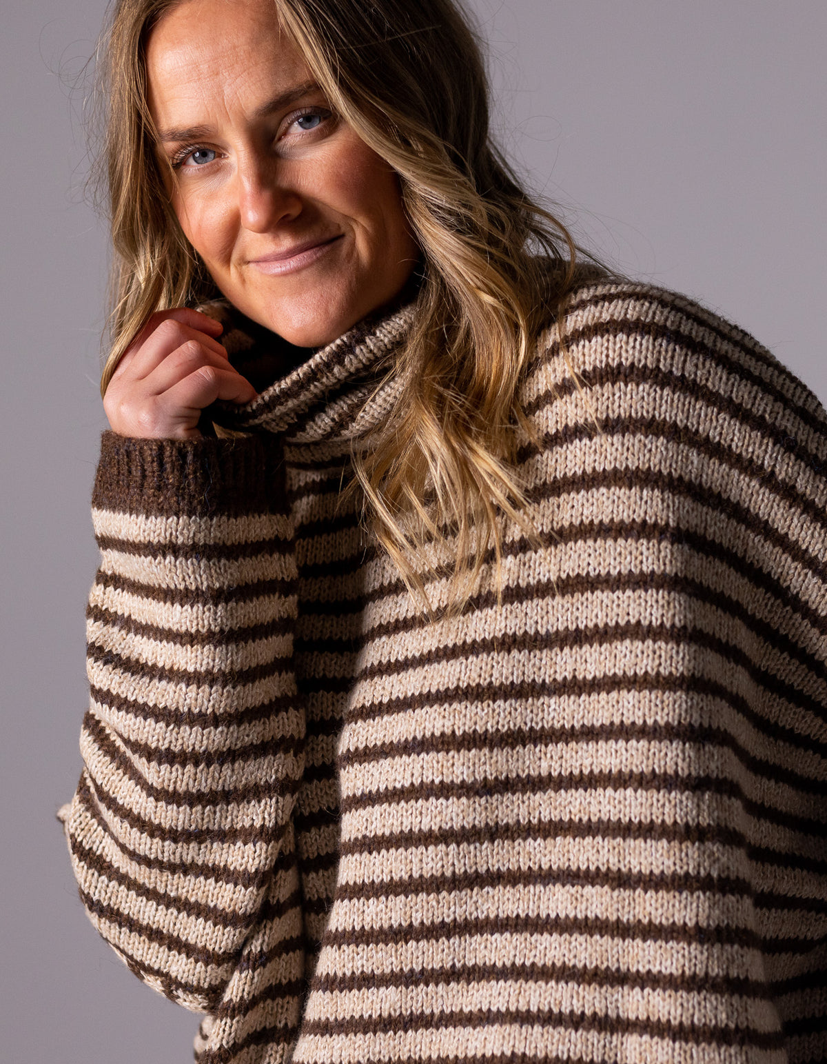 Close-up view of the funnel neck and soft brushed knit fabric on the chocolate and beige stripe jumper.