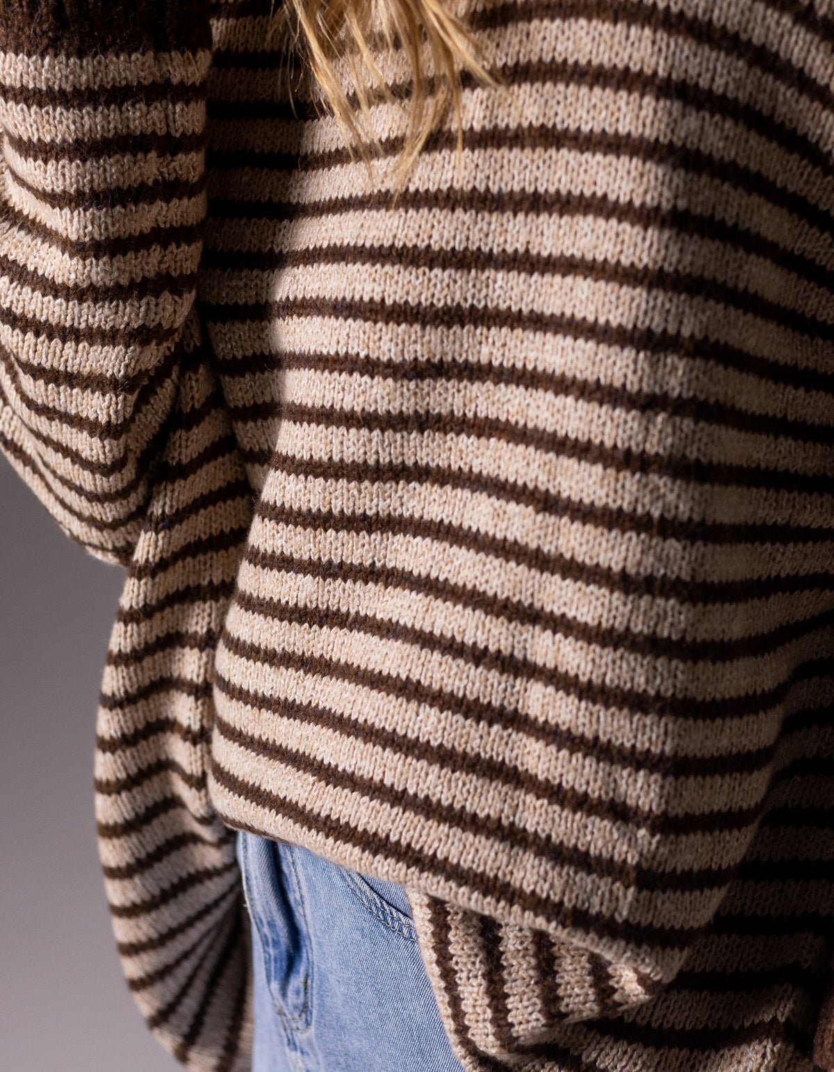 Close-up view of the drop-shoulder sleeve and brushed knit finish on the chocolate and beige stripe jumper.
