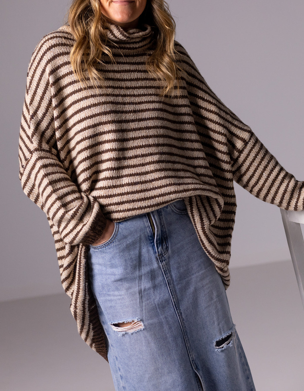 Front half-body shot of the Karma Kameleon chocolate and beige stripe knit jumper and blue denim midi skirt.