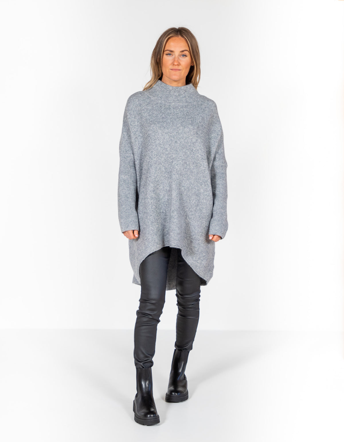 Grey oversized brushed knit jumper featuring a ribbed funnel neck, drop shoulders, ribbed sleeves, and a high-low hem.