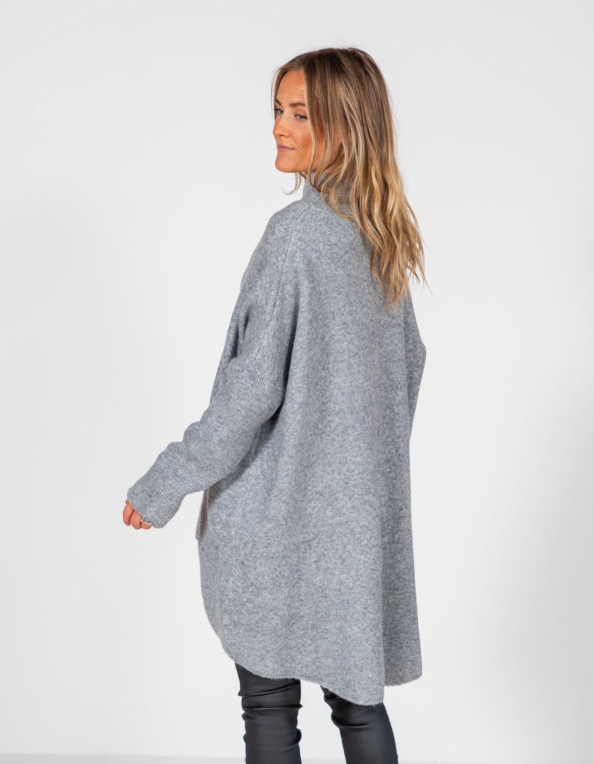 Back view of a grey oversized brushed knit jumper featuring drop shoulders, ribbed sleeves, and a long high-low hemline.