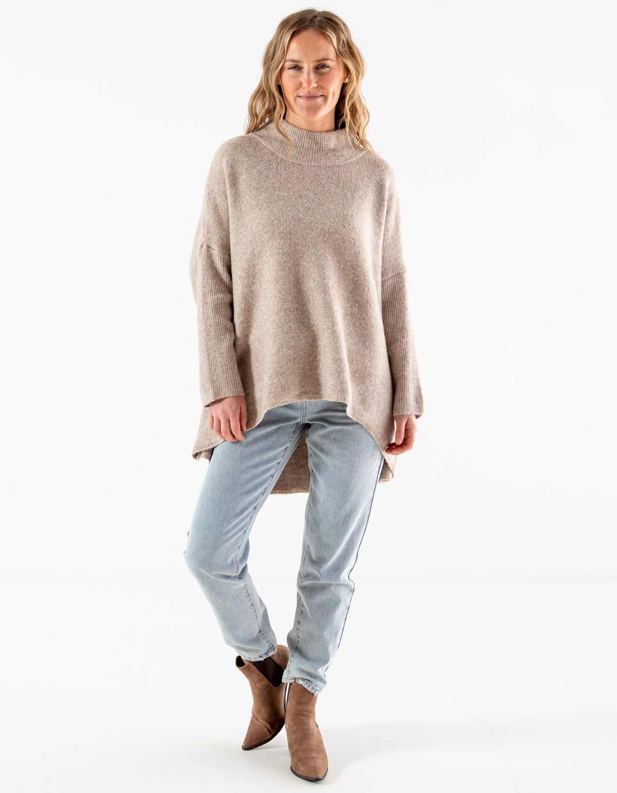 KenFull-length view of the oversized beige brushed knit jumper styled with light wash denim and boots.