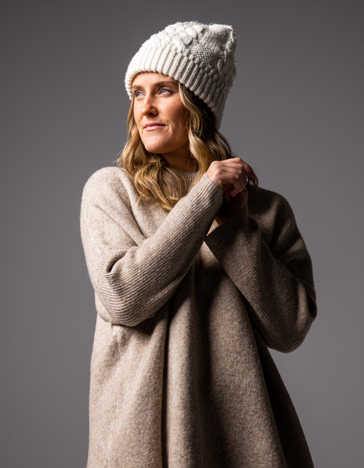 Front half-body shot of the beige Karma Kameleon knit jumper highlighting the oversized fit and ribbed funnel neck.