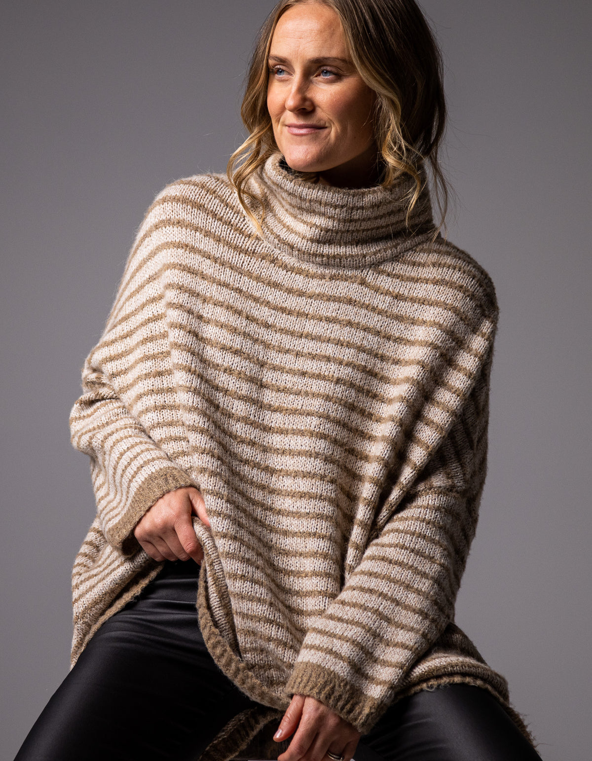 Front half-body shot of the Karma Kameleon beige and mocha stripe knit jumper paired with black pants.