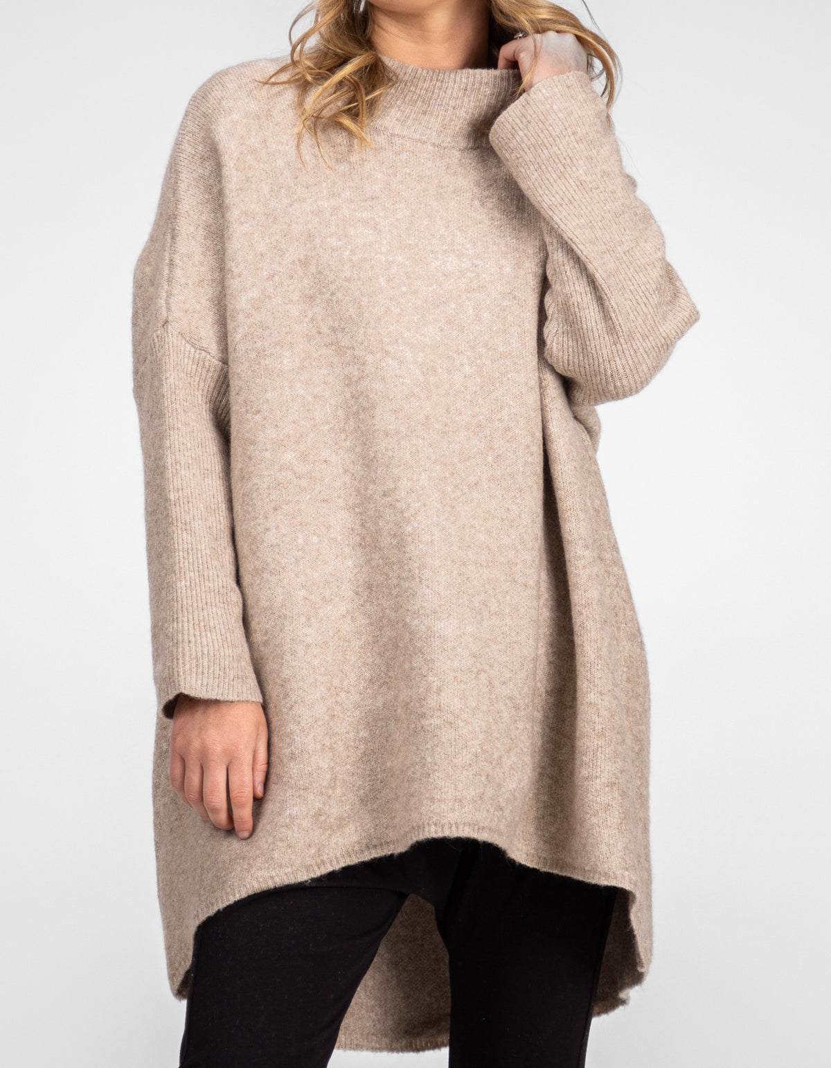 Front half-body shot of the Karma Kameleon beige oversized jumper highlighting the hi-low hemline over black pants.